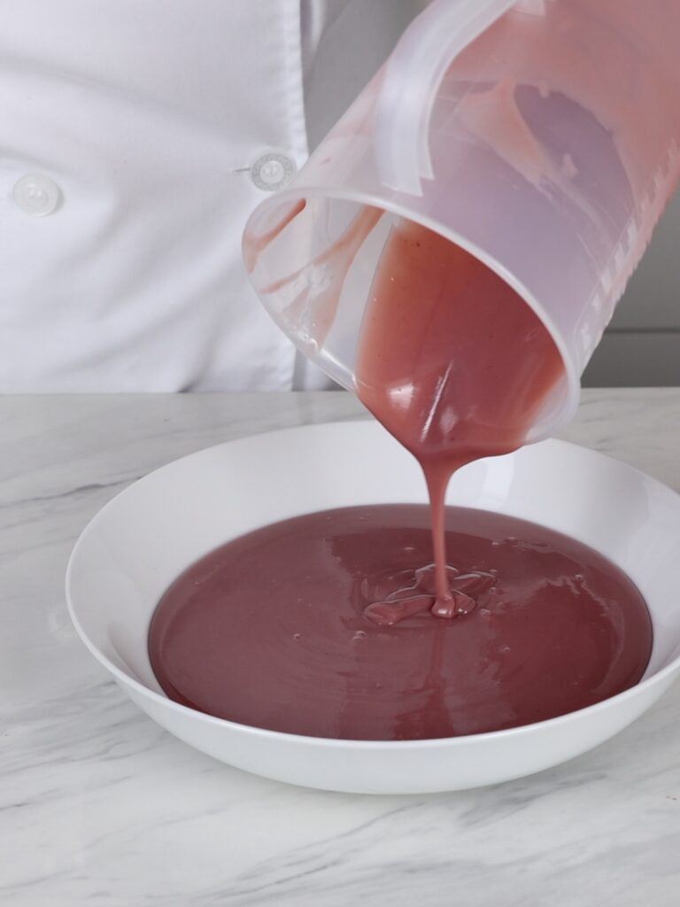 Pouring raspberry ganache into a plate. 