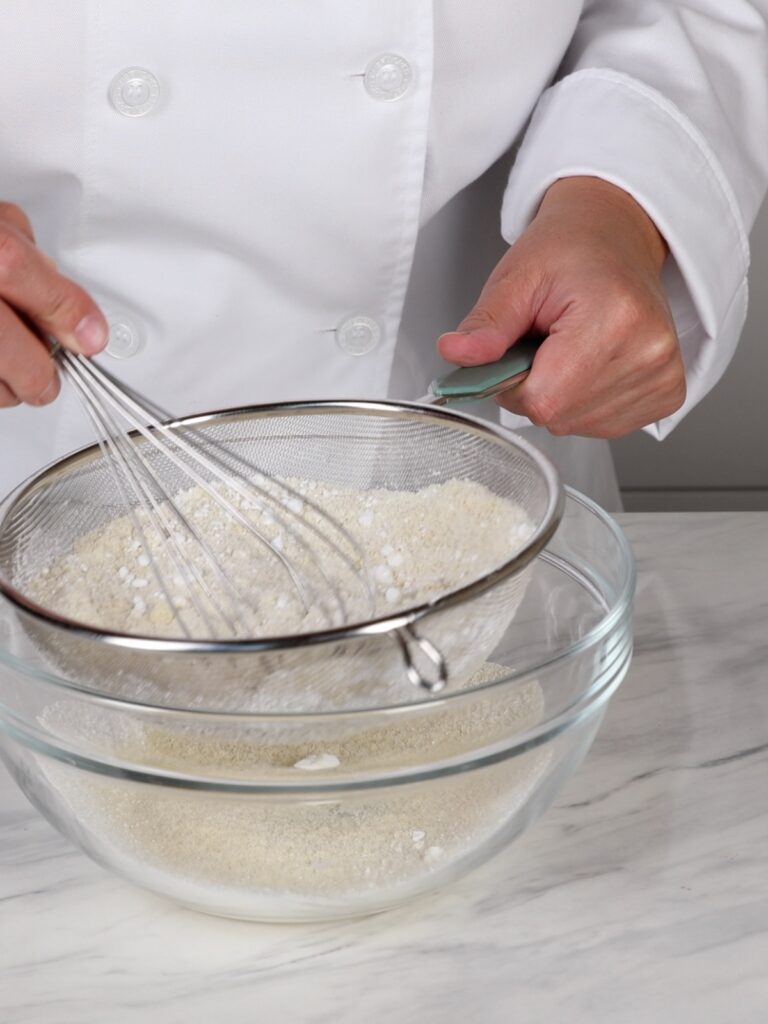 Sifting almond flour with powdered sugar. 