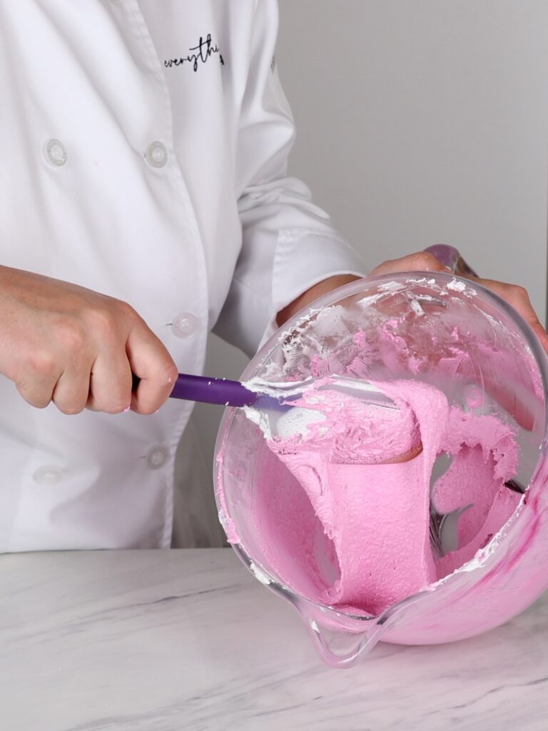 Pink macaronage in the bowl with a spatula. 