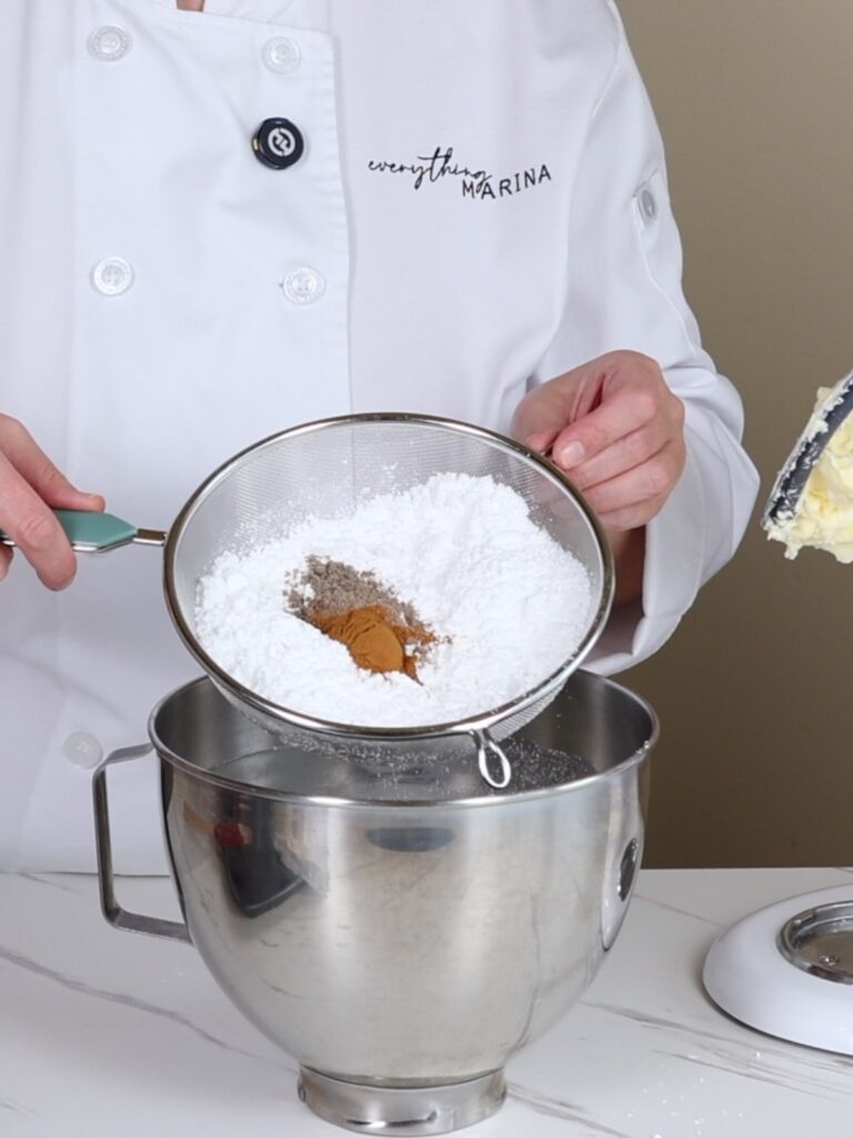 Hands are holding powdered sugar with spices in the sieve.
