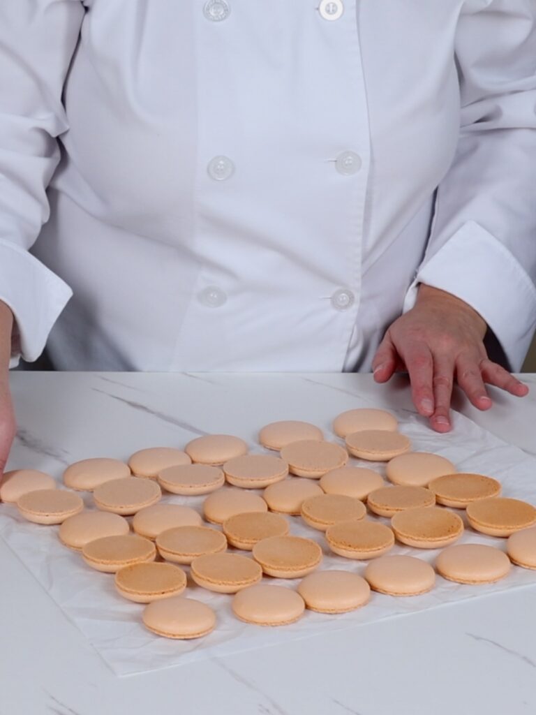 Orange macaron shells on the table.