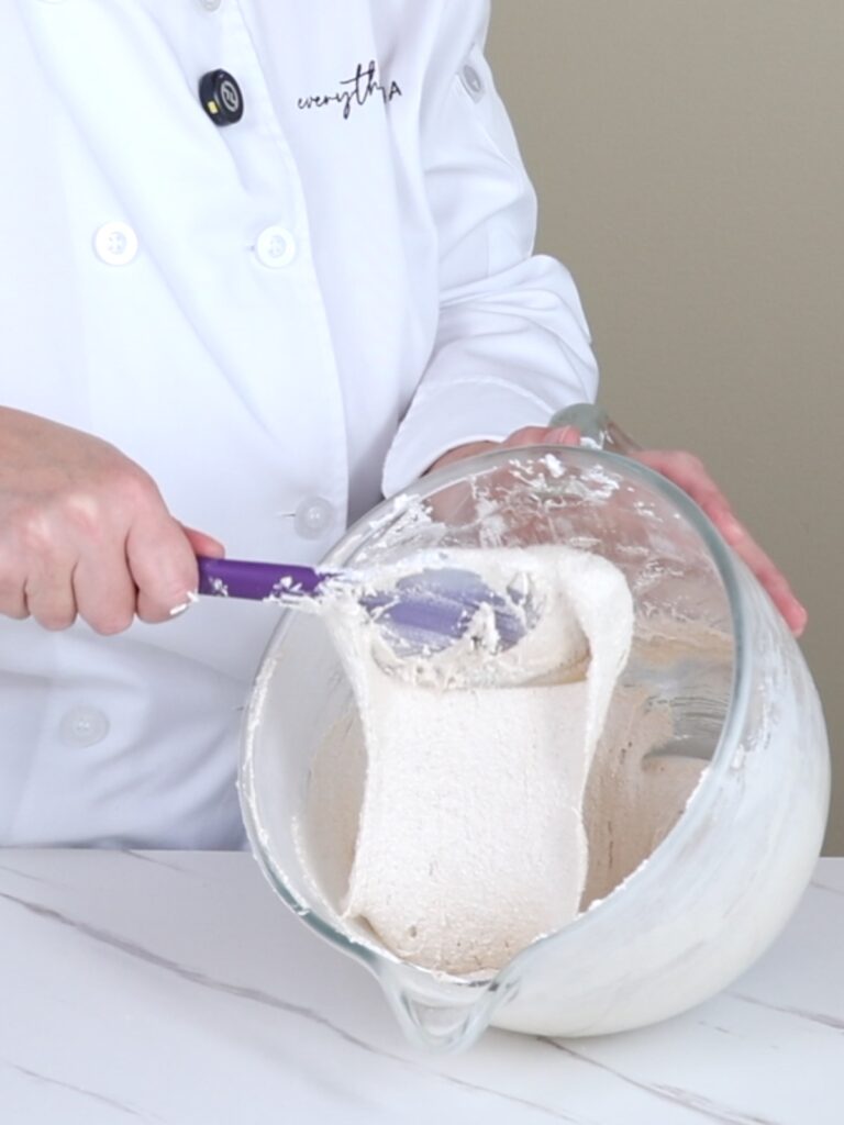 The hand is holding a spatula with macaronage.