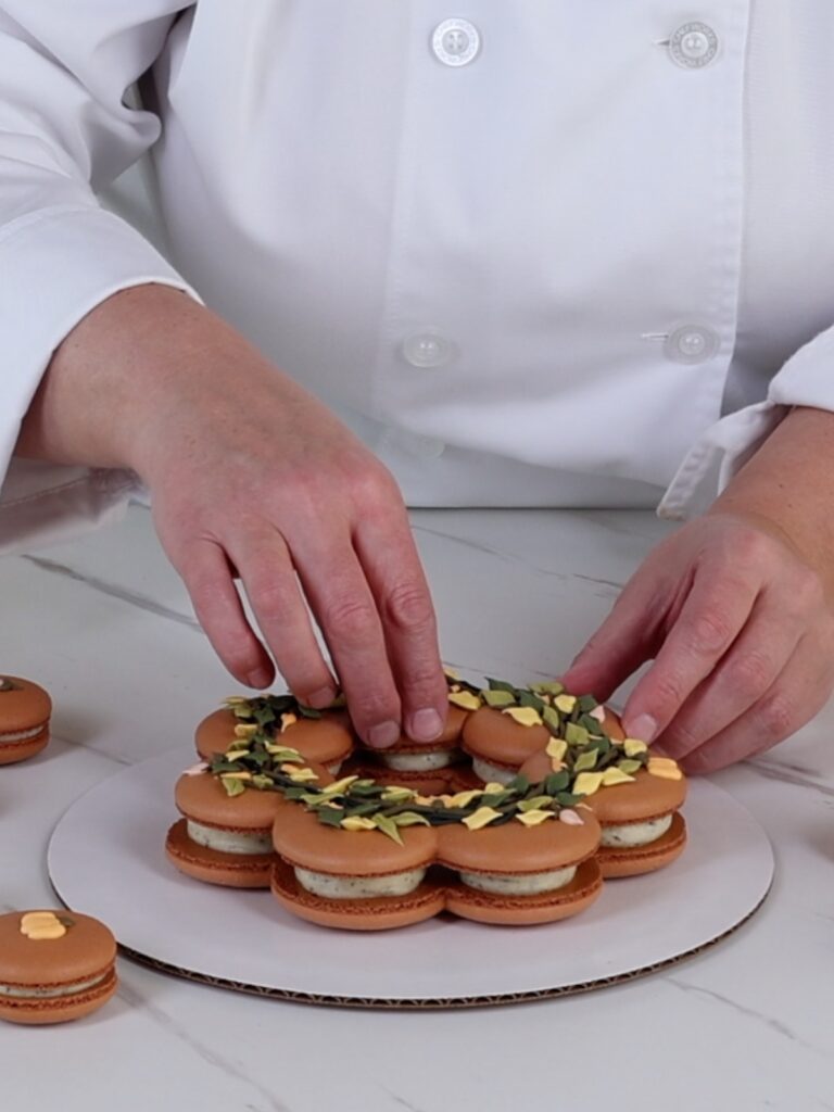 Hands are assembling a macaron wreath.