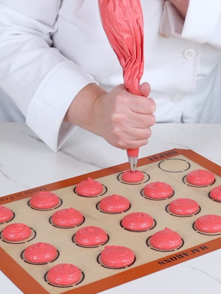 Pipe macaron shells on the baking mat. 