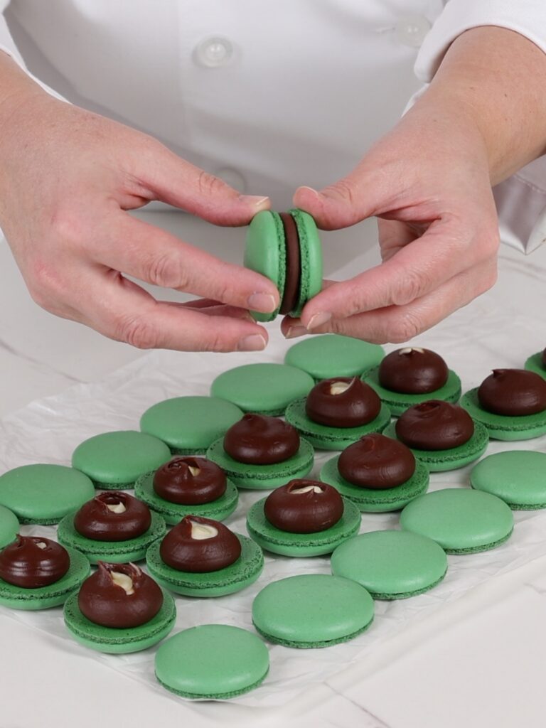 Assembling mint chocolate macarons.