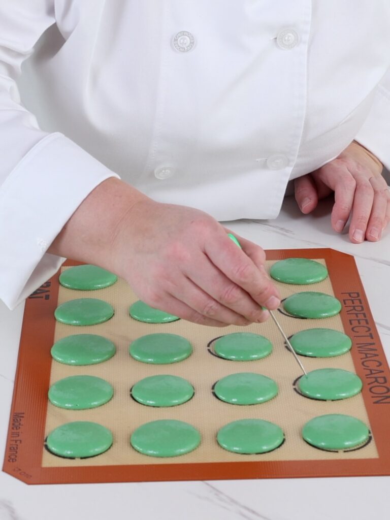 Popping bobbles with the toothpick in the macarons. 