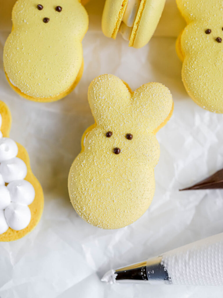 A yellow peep-shaped macaron is on the table. 