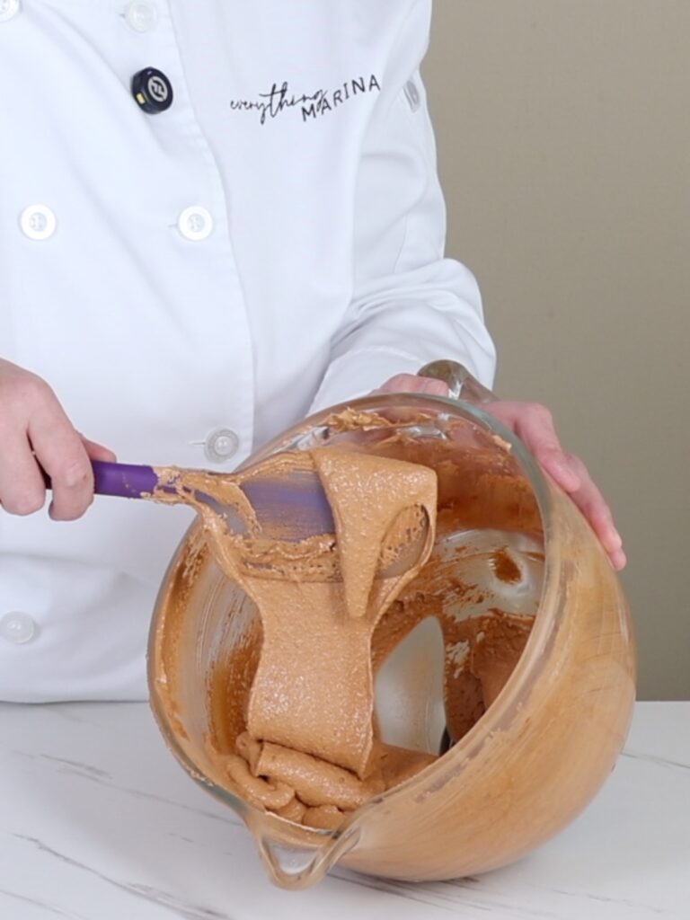 Macaronage flows from the spatula into the mixing bowl. 