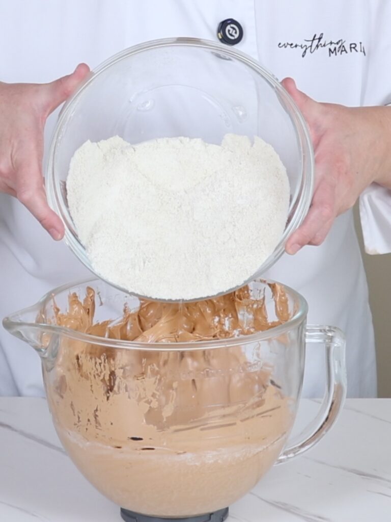 Pouring dry ingredients into the mixing bowl with the French meringue. 
