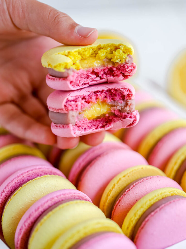 A hand is holding macarons. 