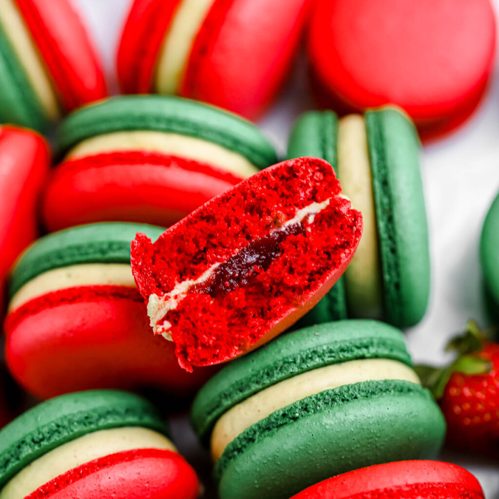 Pistachio Strawberry macarons cut in half on the table.