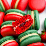 Pistachio Strawberry macarons cut in half on the table.