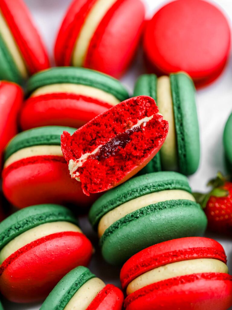 Pistachio Strawberry macarons cut in half on the table. 