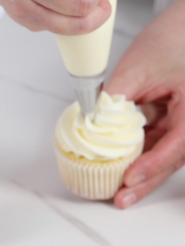 Piping lemon buttercream on the cupcake. 