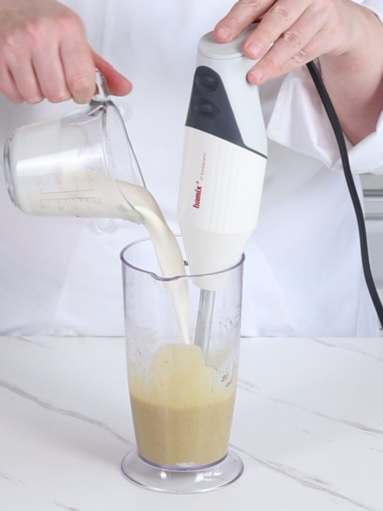 Pouring heavy cream into a tall cup. 