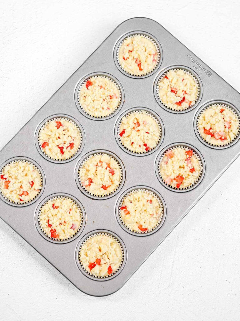 Muffin batter with streusel in the baking tray.