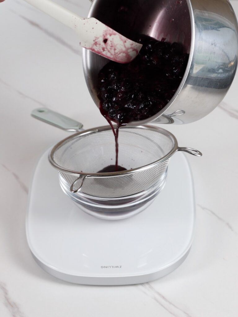 Pouring blueberry puree into a bowl.