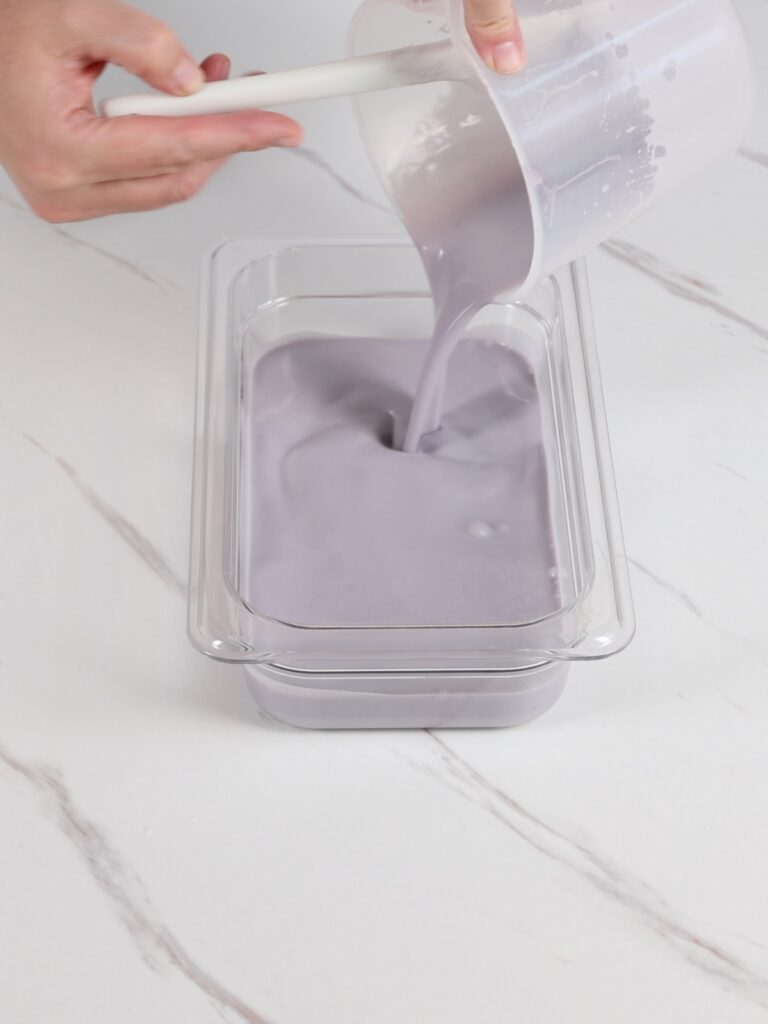 Pouring blueberry ganache into a flat container. 