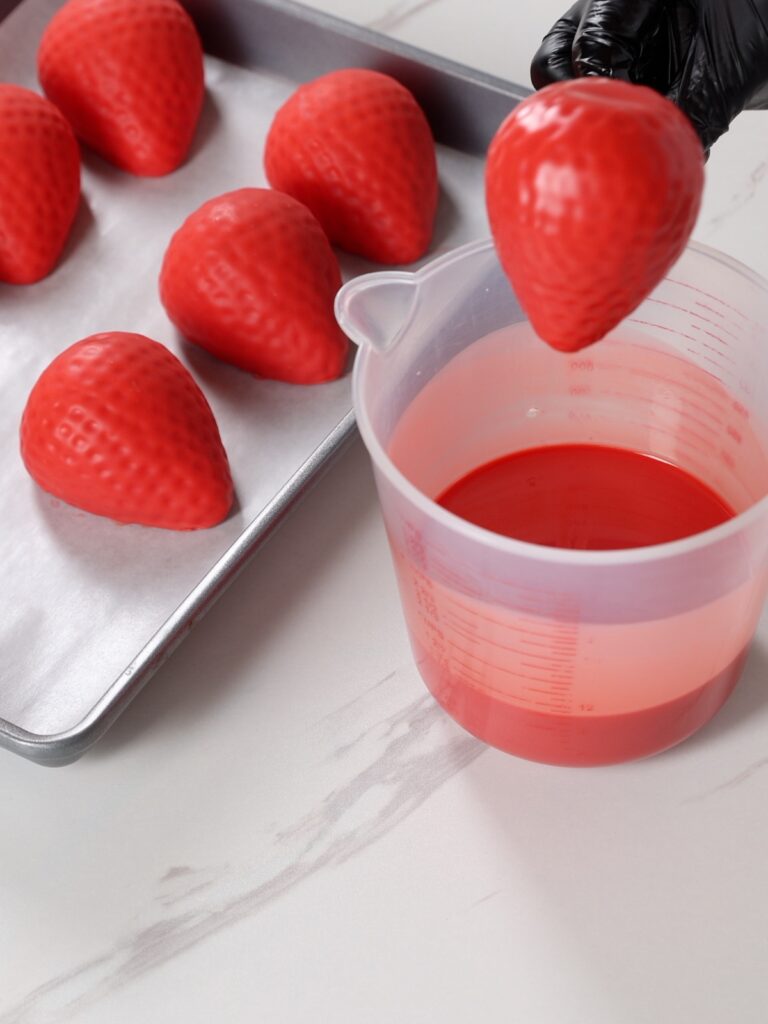 Covering the strawberry in the chocolate.