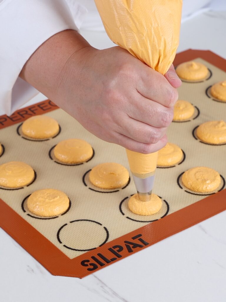 Pipping macarons on the baking mat. 