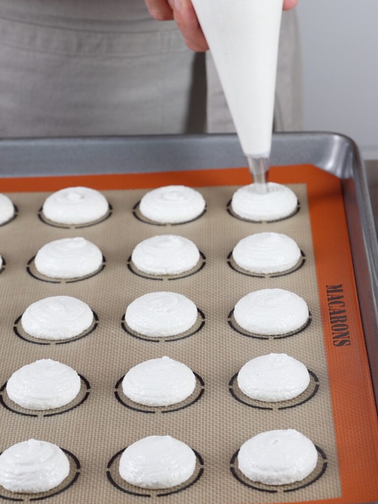 Pipping macarons on the baking mat. 