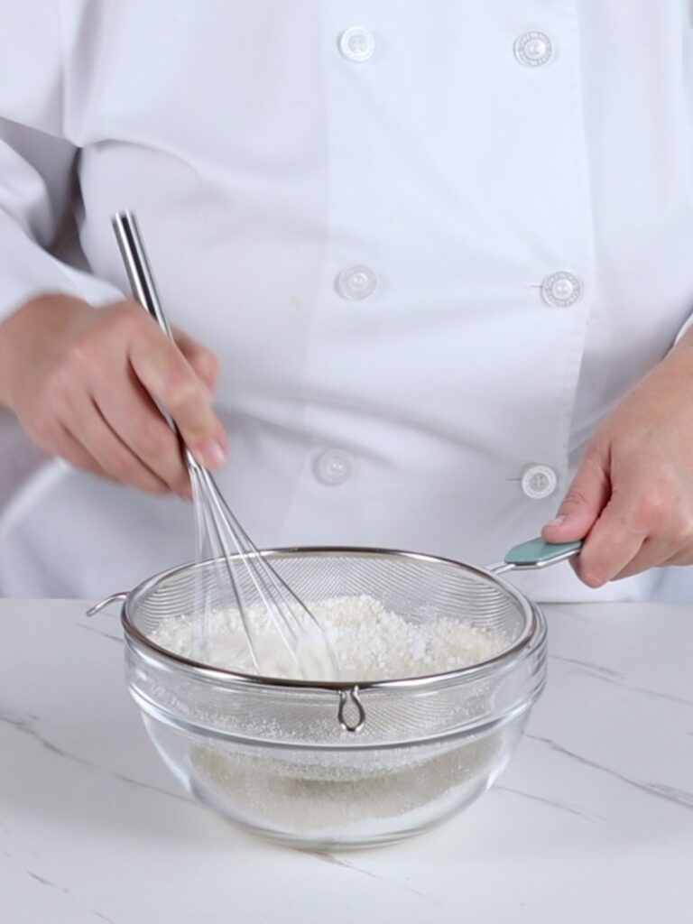 Sifting almond flour and powdered sugar. 