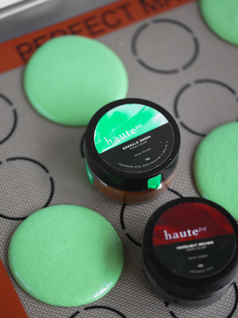 Green macarons with food coloring on the baking mat. 