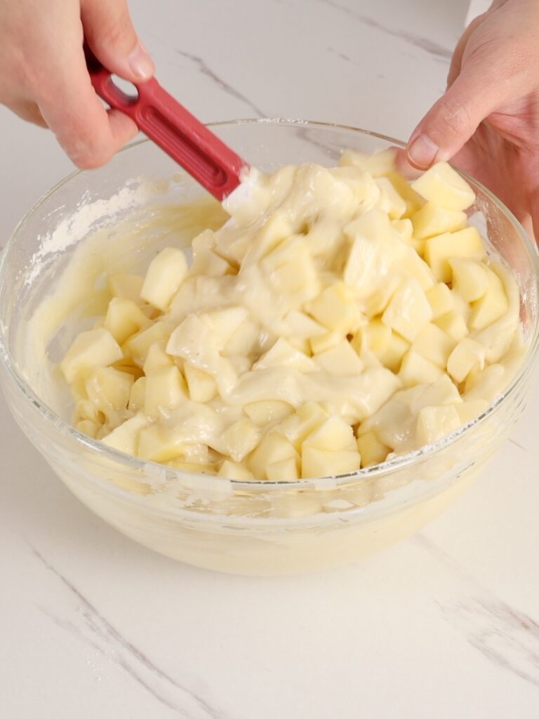 Mixing apple batter with a spatula. 