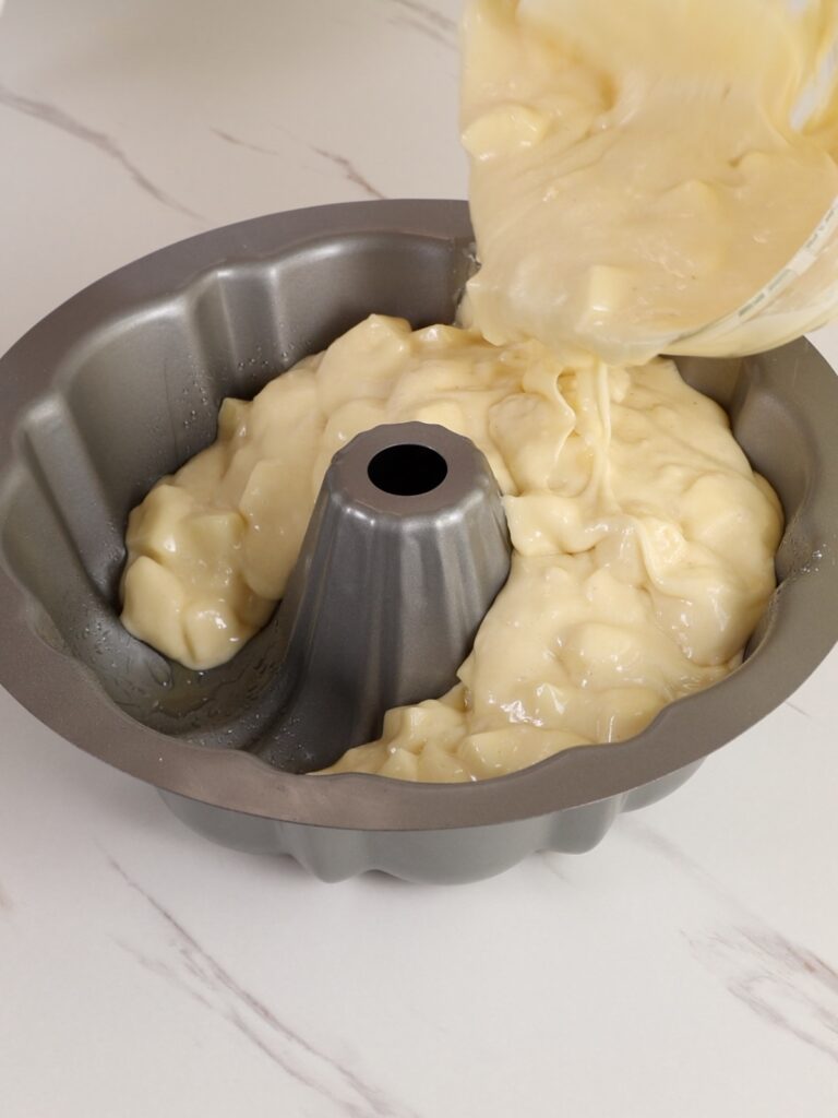 Pouring apple batter into a baking pan. 